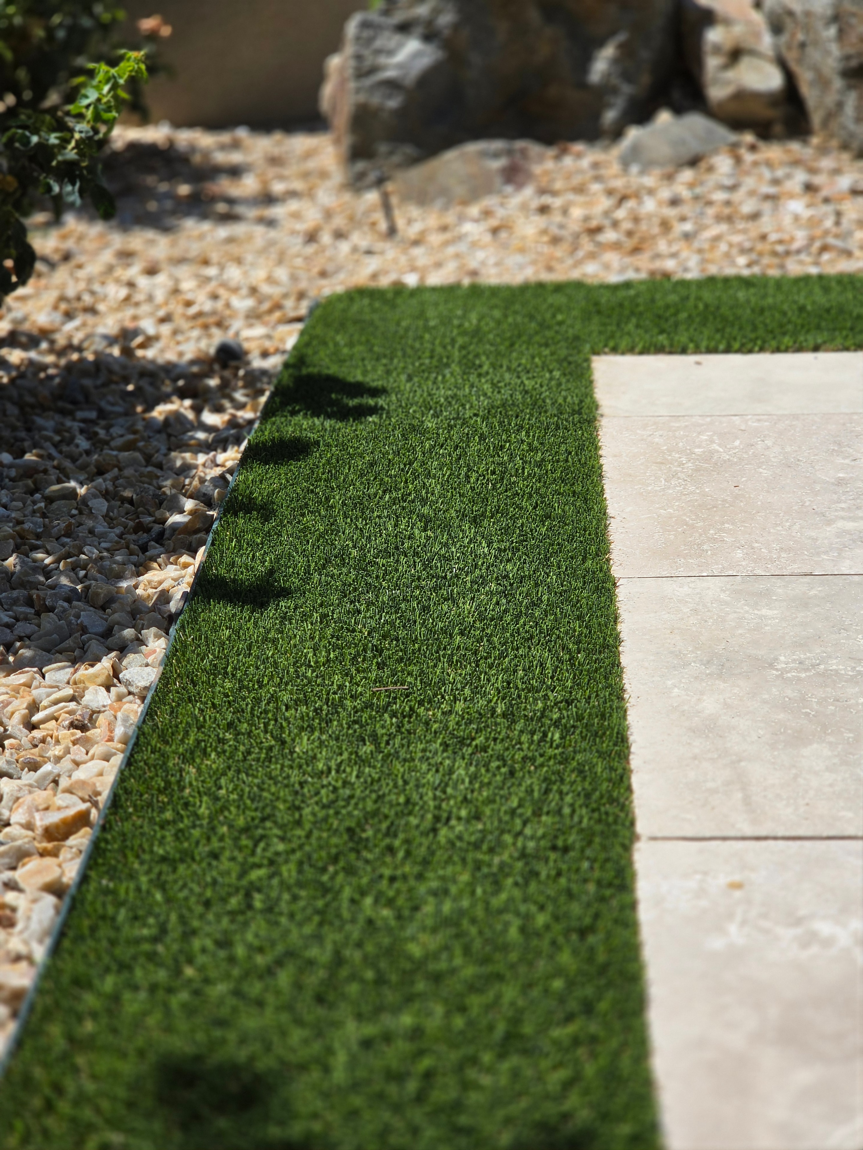 Clean artificial turf edge against stone pavers — precision turf sanitization by Pristine Paws Phoenix AZ